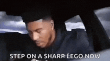 a man is sitting in a car with the words `` step on a sharp lego now '' written on the screen .