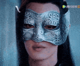 a close up of a man wearing a silver mask with chinese writing on it