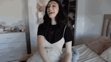 a woman with a tattoo on her arm is sitting on a bed and smiling