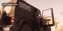 a man is getting out of a jeep with the doors open