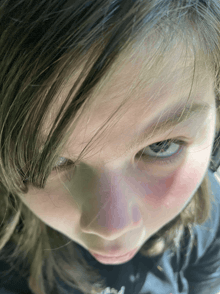 a close up of a girl 's face with a black shirt that says ' a ' on it