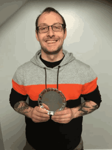 a man with a tattoo on his arm is holding a trophy and smiling