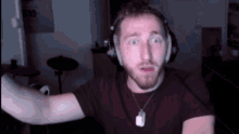 a man wearing headphones and a dog tag around his neck looks surprised