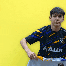 a young man holds up a shirt that says aldi