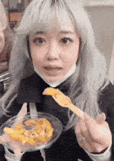 a woman with a mask on her face is holding a plate of food in her hands