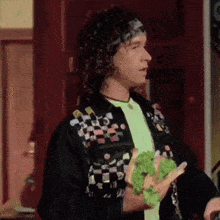 a man with curly hair is holding a sandwich in his hands .