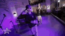 two men are dancing on a stage with purple lights and a cyberstar logo in the corner .
