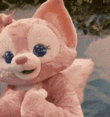 a pink stuffed animal with blue eyes is sitting on a table .