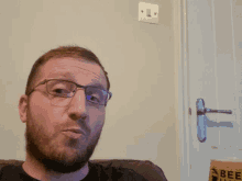 a man with glasses and a beard is sitting in front of a glass that says beef hawk