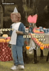 a little boy wearing a party hat is standing in front of a table with hearts on it and says happy birthday .