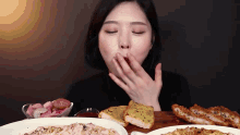 a woman is covering her mouth with her hand while eating a variety of food