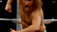 a man with a beard is in a wrestling ring without a shirt on .