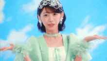 a woman in a green dress with ruffled sleeves and a tiara on her head