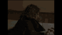a man with long hair and a beard is brushing his teeth in a dark room .