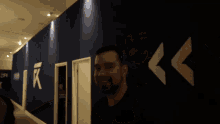 a man stands in a hallway with a sign on the wall that says ' r '