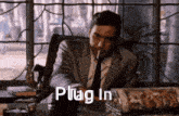 a man in a suit and tie is smoking a cigarette and the words plug in are displayed above him