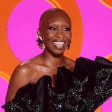 a woman with a shaved head is wearing a black dress