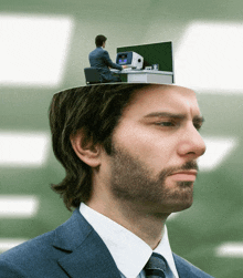 a man in a suit has his head open and a man sitting at a desk on top of his head
