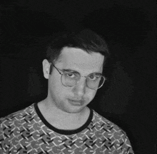 a man with glasses and a patterned shirt looks at the camera