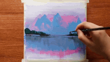 a person is painting a landscape of mountains and a lake