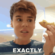 a young man is holding a piece of food and the word exactly is on the bottom right