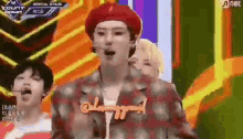 a man wearing a red beret and a plaid jacket is standing on a stage .