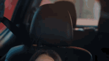 a woman is sitting in the back seat of a car with her head resting on the seat belt