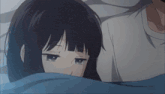 a girl is laying in bed with a man and hiding behind a blue blanket .