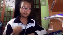 a young girl wearing glasses and a jacket is standing in a room .
