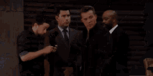 a group of people are standing around a man in a suit .