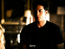 a man in a black shirt says " sorry " in a dark room