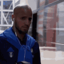 a man wearing ear buds and a blue adidas jacket