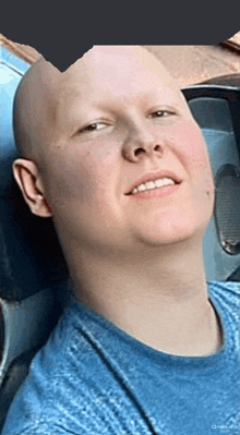 a man with a shaved head is wearing a blue shirt