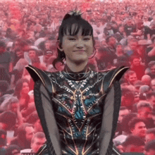a woman in a costume is smiling in front of a crowd of people at a concert .