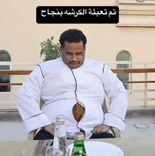 a man is sitting at a table with a bottle of water and a plate of food