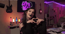 a woman making a heart shape with her hands in front of a tv that says life is wiz