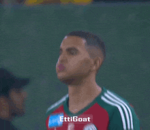 a soccer player wearing a red and green jersey that says ettigoat on it