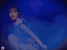 a woman in a crop top and shorts is dancing on a stage in a dark room .