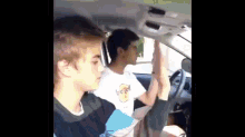 two young men are sitting in a car with one wearing a hard rock t-shirt .