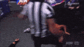 a wrestler is laying on the ground while a referee looks on .