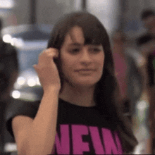 a woman wearing a black shirt that says new