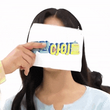 a woman is covering her face with a piece of paper with the word jojo on it .
