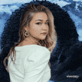 a woman wearing hoop earrings is standing in front of a stone archway with the words vivavideo written on the bottom