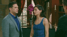 a man in a suit and a woman in a blue tank top are standing next to each other