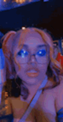 a woman wearing glasses and pigtails is looking at the camera .