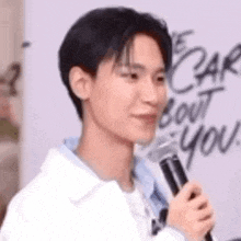 a young man is holding a microphone in front of a wall .