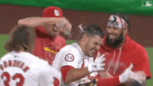 a group of baseball players are hugging each other and laughing on the field .