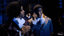 two men are standing next to each other on a stage with a disney + logo in the corner