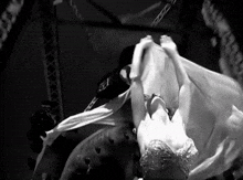a black and white photo of a woman hanging from a rope