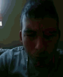 a man with his eyes closed is wearing a silver chain around his neck
